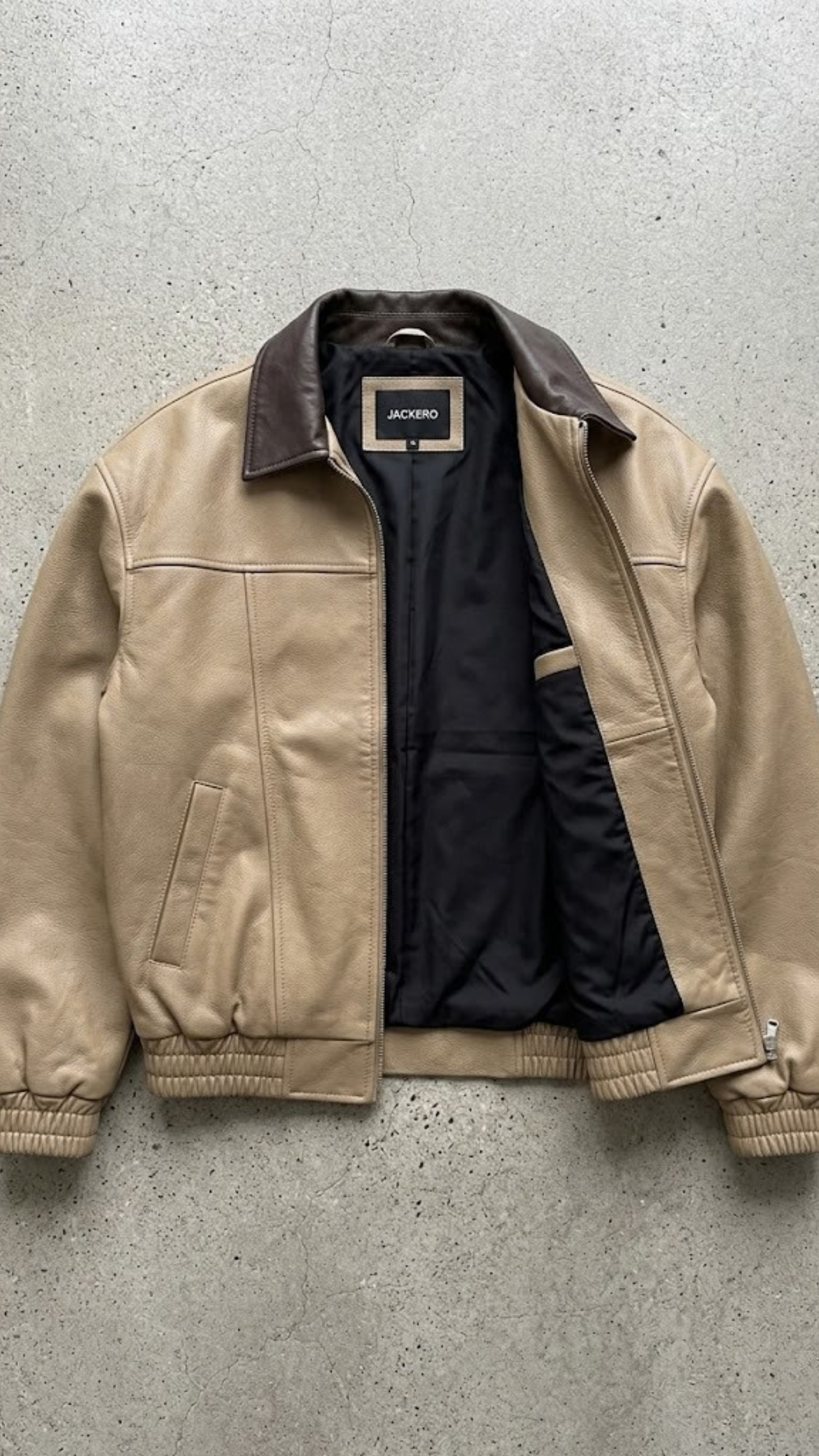 Beige jacket with black lining on a gray concrete surface
