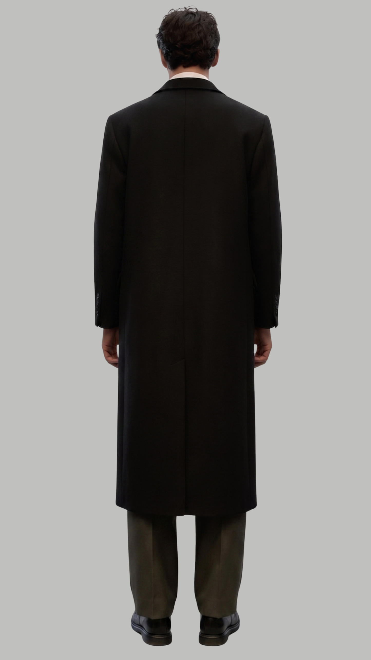 Full-length view of a sophisticated black long wool coat paired with formal attire.