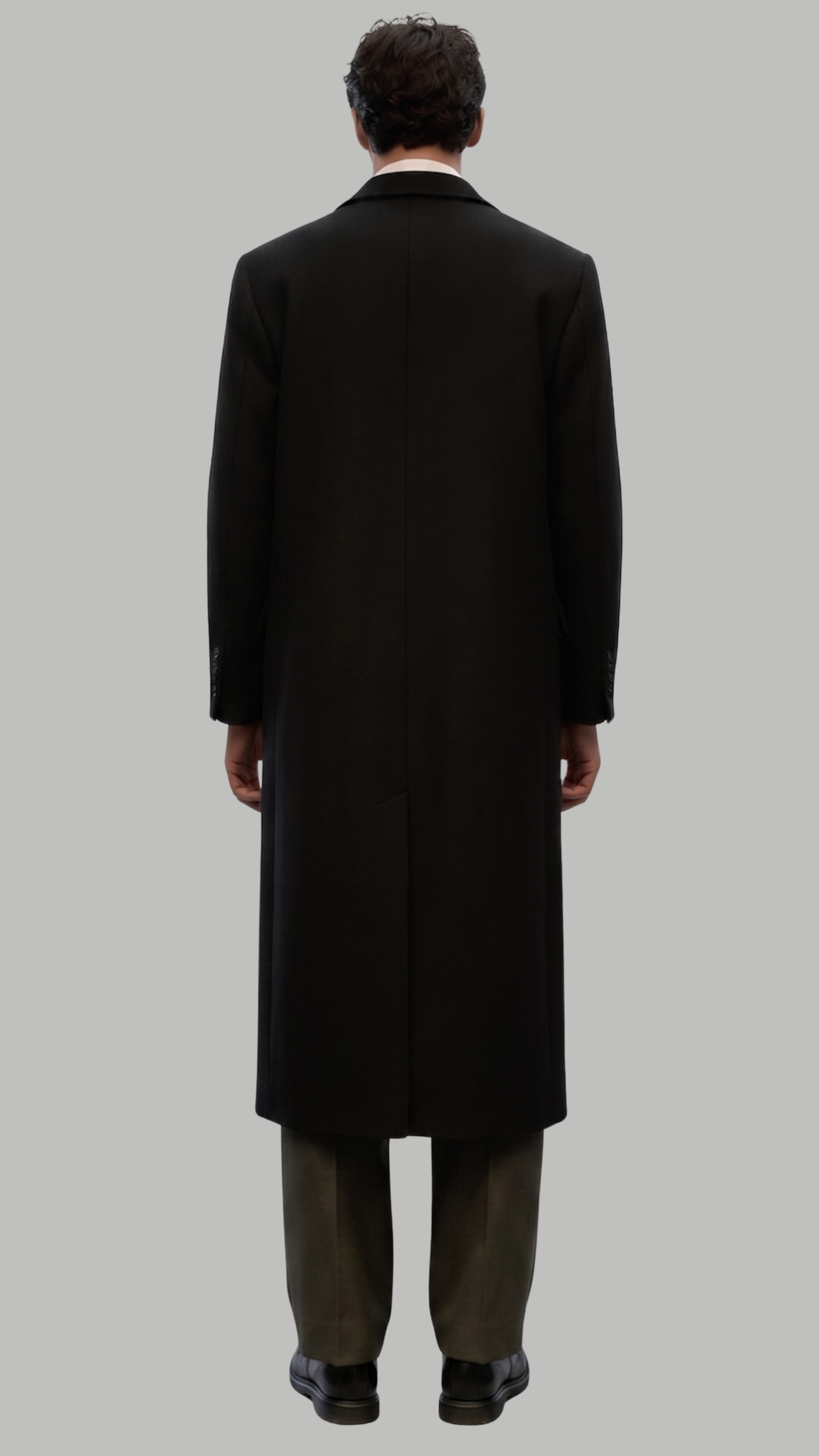 Full-length view of a sophisticated black long wool coat paired with formal attire.