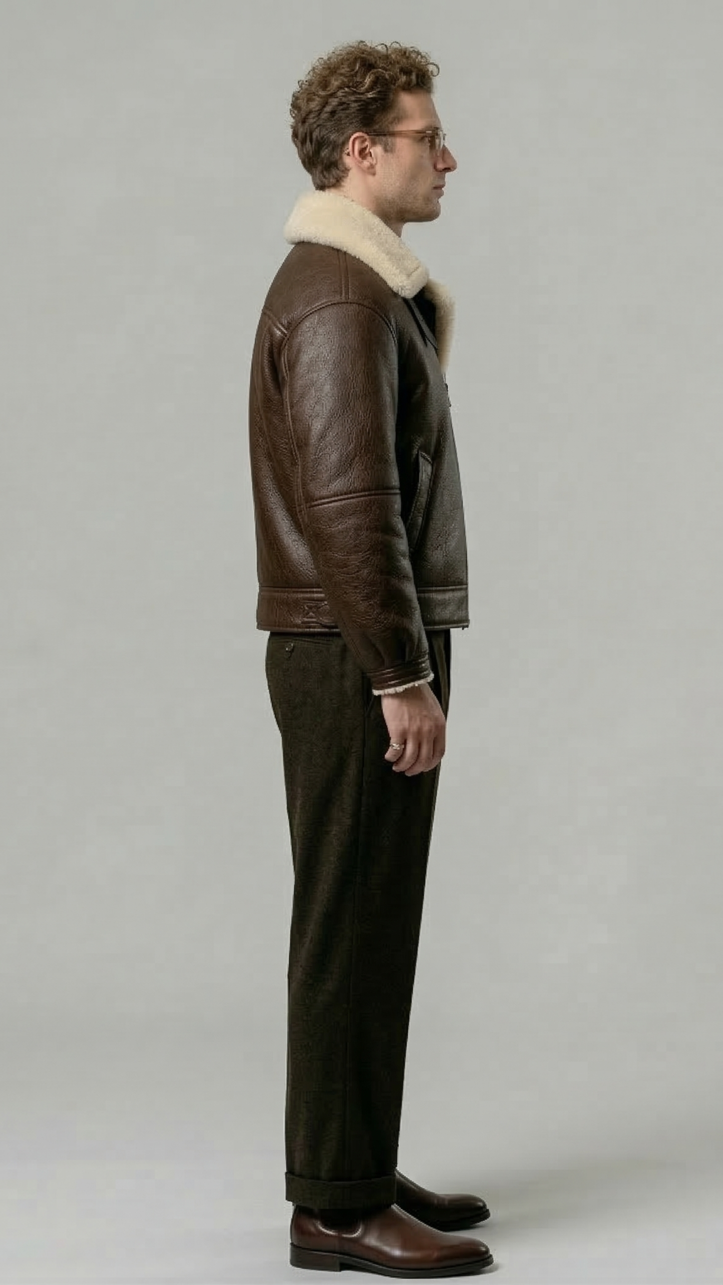 Minimalist catalog style photography of a premium dark brown leather outerwear coat with soft cream fur accents on a solid neutral background.
