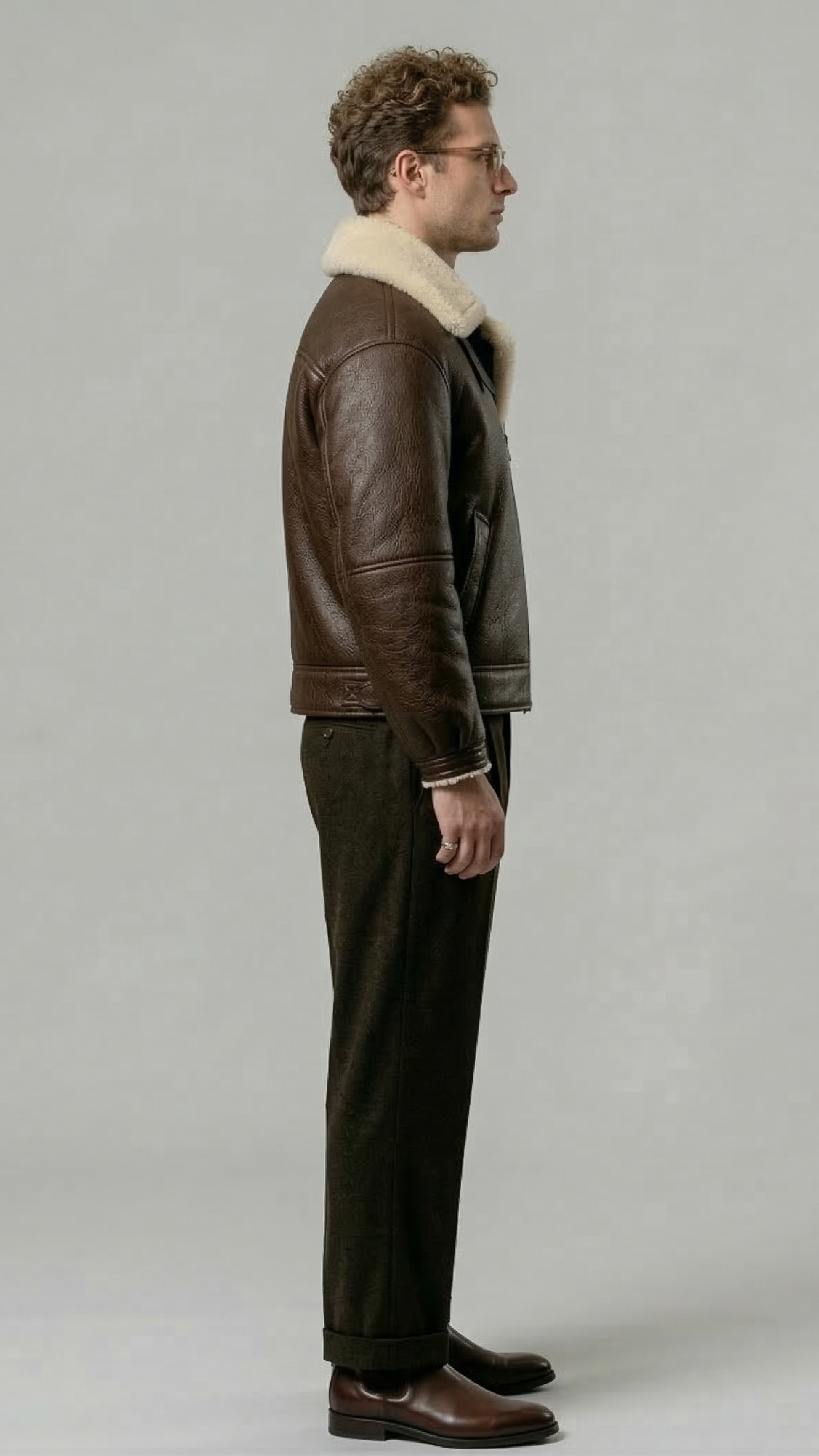 Minimalist catalog style photography of a premium dark brown leather outerwear coat with soft cream fur accents on a solid neutral background.