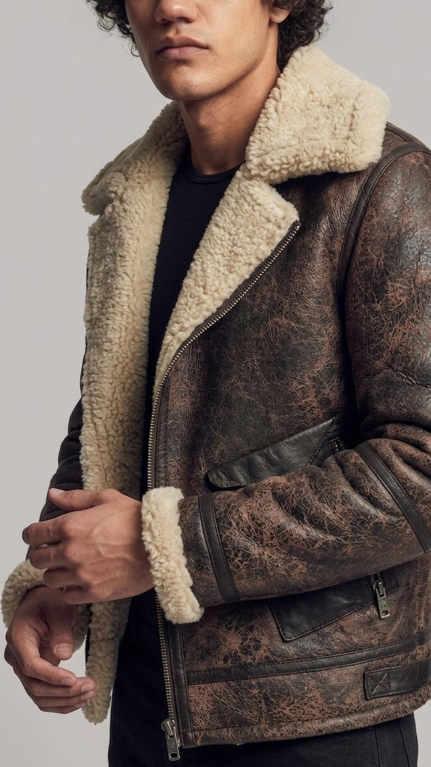 Close-up of the rugged distressed leather finish and soft cream shearling details on a brown flight jacket.