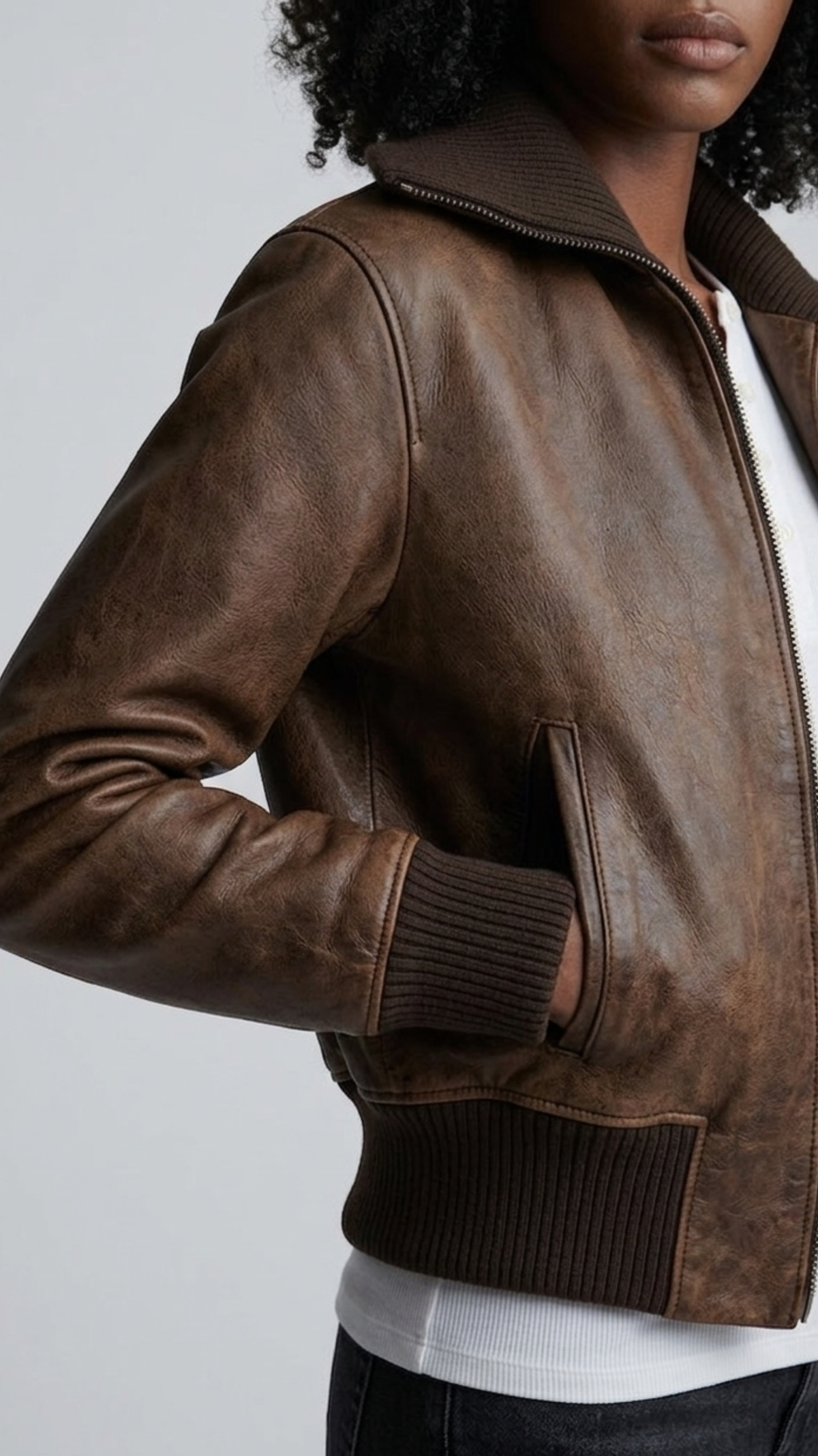 Detailed macro close-up shot capturing the heavy premium hide grain and rich espresso finish of the authentic dark brown leather bomber fabric.
