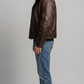 Side-profile view of a structured dark brown leather aviator coat showcasing the clean silhouette and prominent black shearling.
