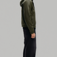 Model wearing a custom-fit dark green leather flight bomber jacket with a cozy shearling hood against a clean studio backdrop.