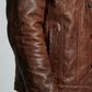 Macro detailed close-up capturing the unique vintage weathered texture and aged patina marks on the dark tan genuine leather fabric.