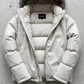 White puffer jacket with fur hood on a gray concrete surface