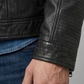 Close-up micro detail highlighting the smooth premium finish and fine tailored stitching of a solid black leather trucker outerwear.
