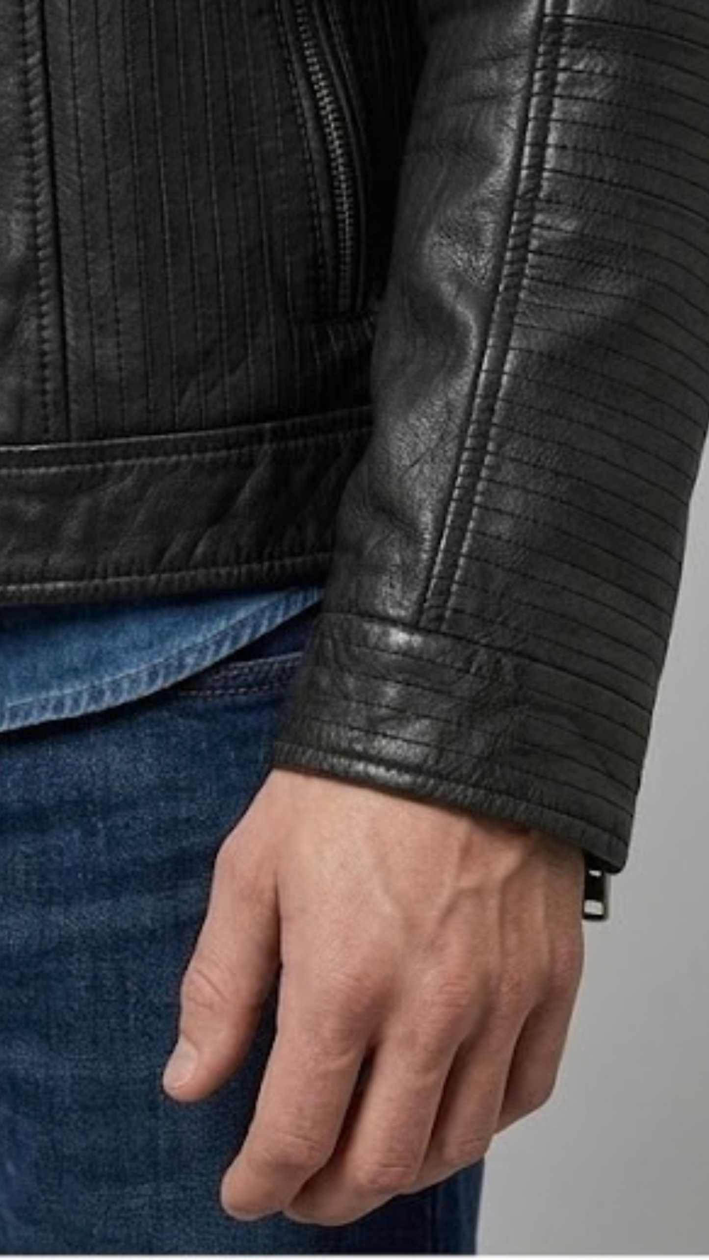 Close-up micro detail highlighting the smooth premium finish and fine tailored stitching of a solid black leather trucker outerwear.