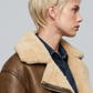 Close-up shot of handcrafted genuine brown leather material and soft cream shearling cuffs on a luxury winter coat.