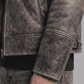 Close-up of the rugged distressed leather texture in dark grey with soft white fur lining details.