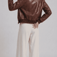 Model wearing a brown croc-embossed leather jacket over a black henley shirt paired with off-white wide-leg trousers.
