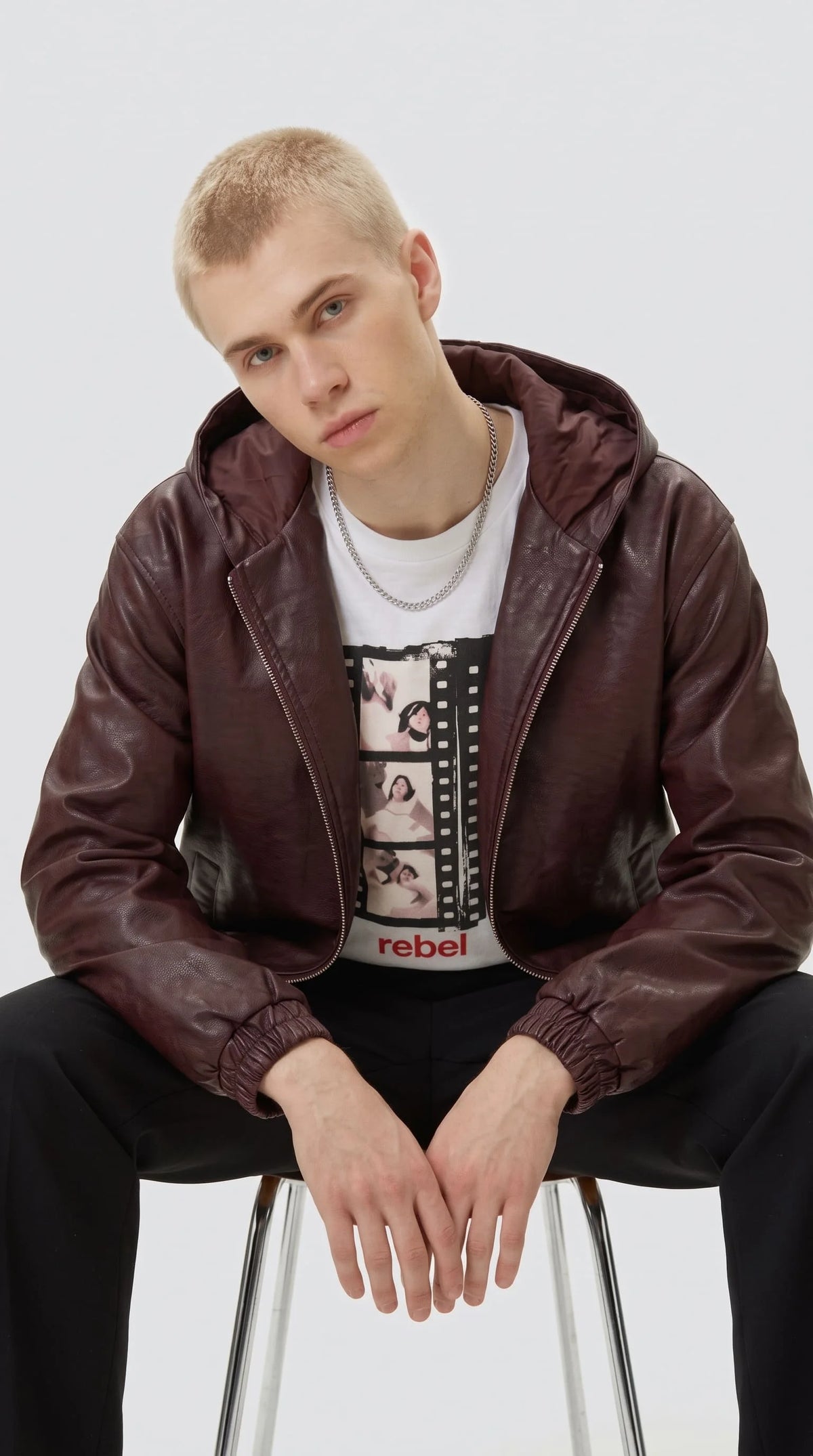 Cropped boxy fit maroon real leather bomber jacket with hood and side pockets, modeled by young man.