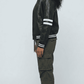 Woman wearing a fitted premium black leather cafe racer jacket standing straight in a professional studio setting.