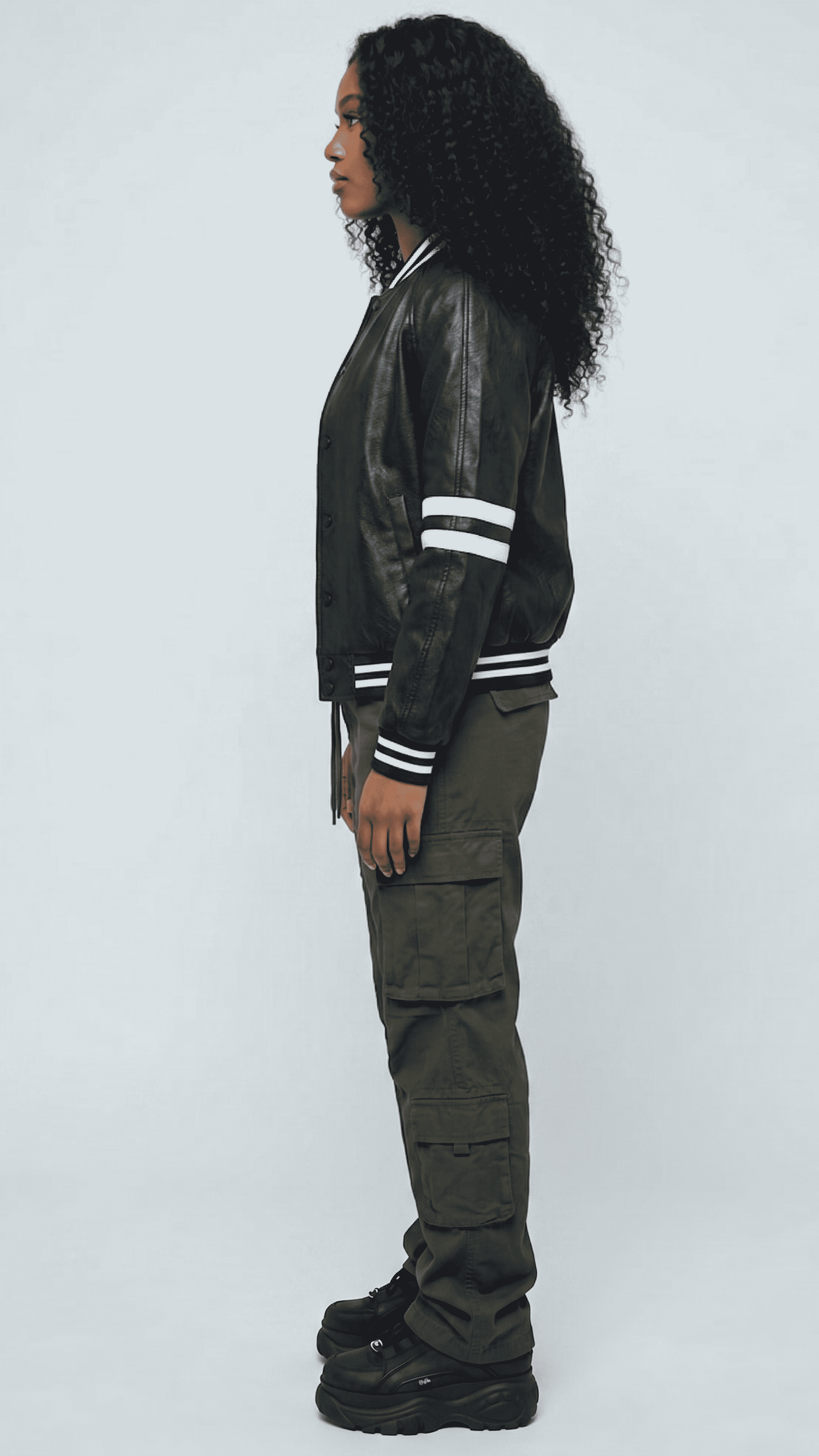 Woman wearing a fitted premium black leather cafe racer jacket standing straight in a professional studio setting.
