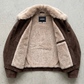 High-grade dark brown leather material close-up on an outerwear coat with soft plush wool lining visible along the neck lapels.