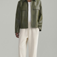 Man wearing a green leather jacket and beige pants on a white background