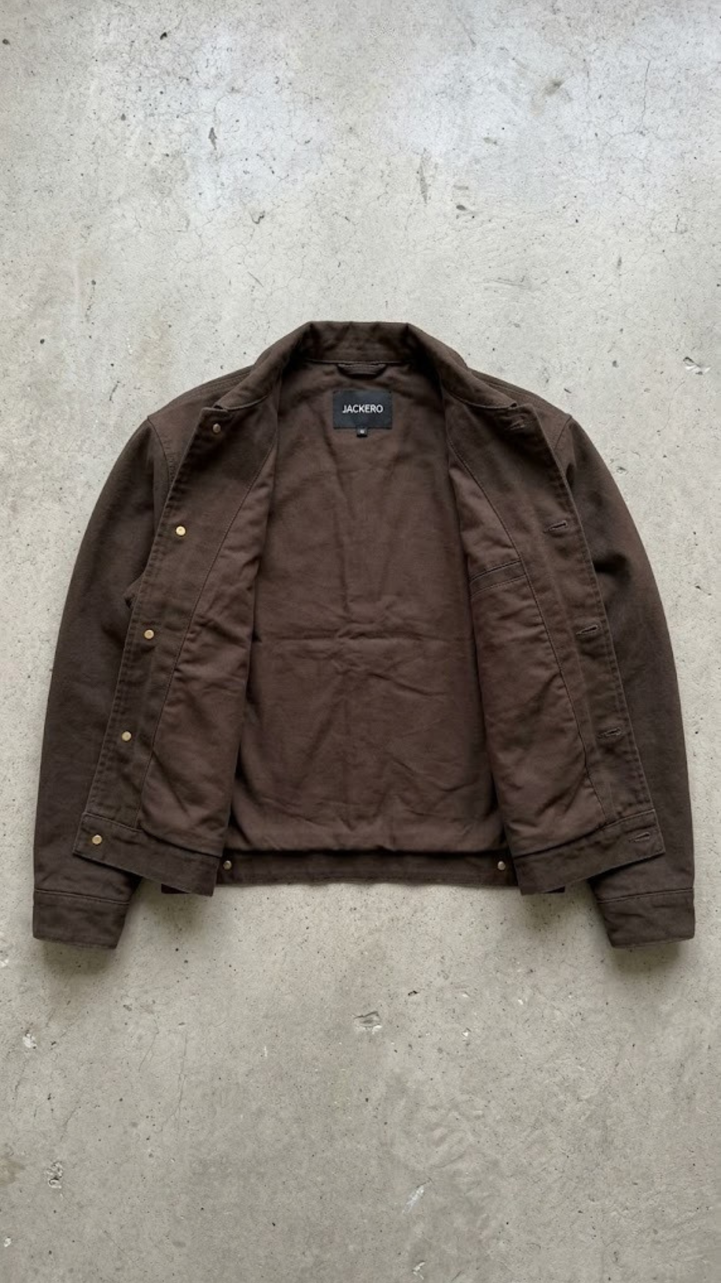 Brown canvas jacket on a gray concrete surface