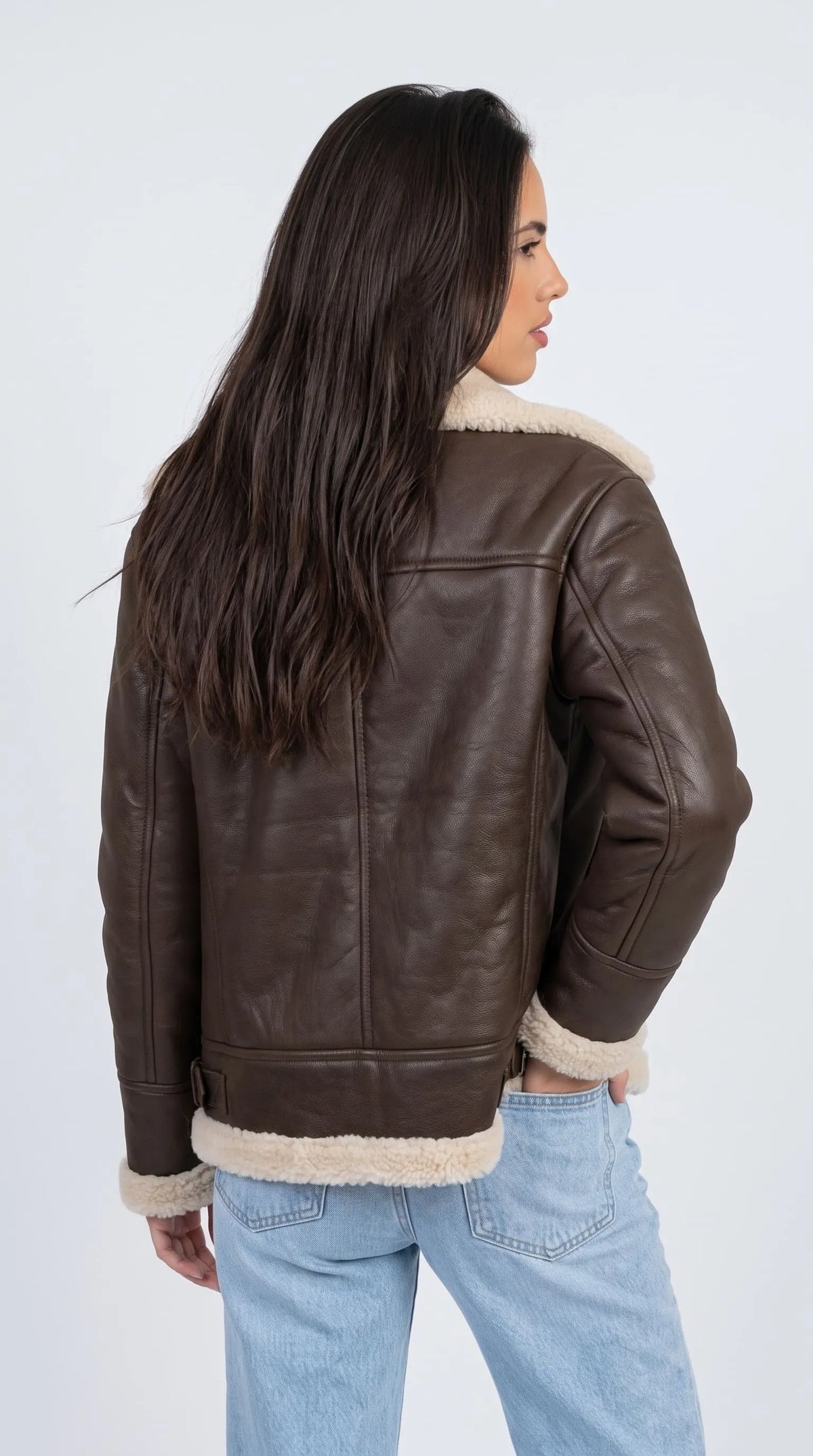 Dark chocolate-brown genuine leather flight jacket featuring a structured horizontal back yoke, clean vertical panel stitching and a broad off-white faux-shearling collar. Matching cream shearling along the cuffs and lower hem adds contrast to the deep brown leather, while the relaxed oversized cut delivers a heritage aviator appearance suited to vintage-inspired outfits and everyday winter layering.