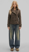 Full body view of a women wearing a dark brown short wool pea coat with a structured fit.