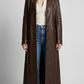 Full-length shot of a women wearing a dark chocolate brown leather trench coat.