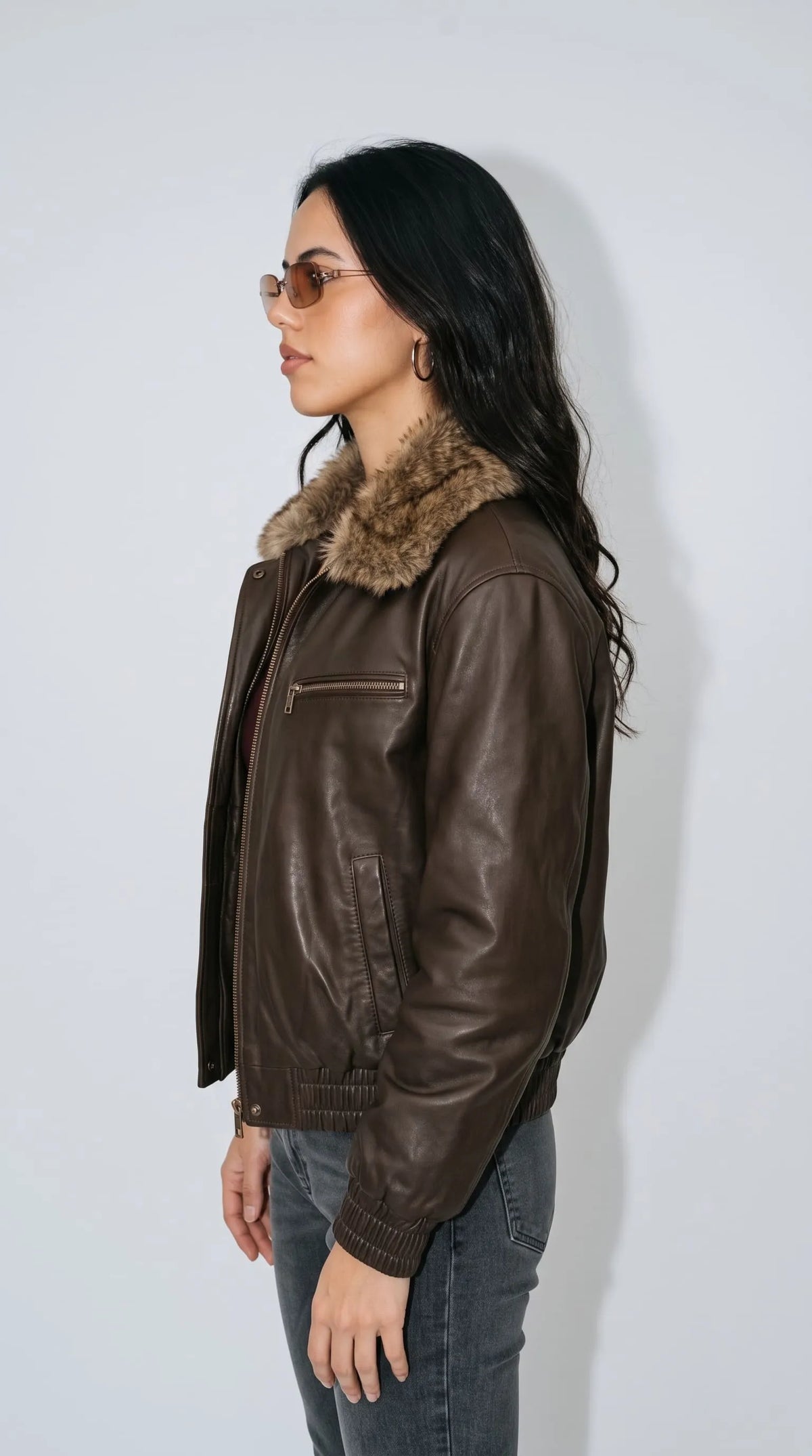 Dark brown distressed leather aviator bomber jacket with a voluminous faux-fur collar, relaxed shoulders, full metal front zipper and elasticated rib-knit cuffs and waistband. Styled with faded charcoal denim, the roomy silhouette and warm brown leather finish create a versatile casual layering piece that blends heritage flight-jacket styling with contemporary oversized street fashion.