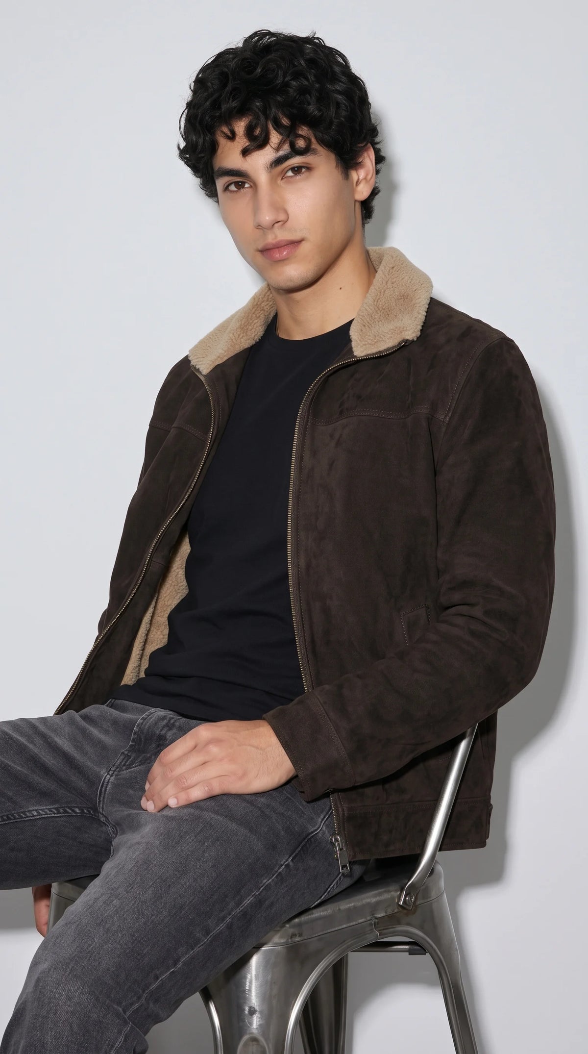 A men's dark espresso suede jacket with contrasting cream shearling trim delivers an aviator-inspired aesthetic with a modern, wearable silhouette. Its rich brown surface, cosy statement collar and practical zipped front bring together vintage flight-jacket character and contemporary streetwear, creating a distinctive outerwear look for cold city days and casual winter outings.