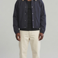 Front view studio catalog photo of a model styling the Jackero dark navy blue cotton coach jacket with a classic collar and visible snap button closures.