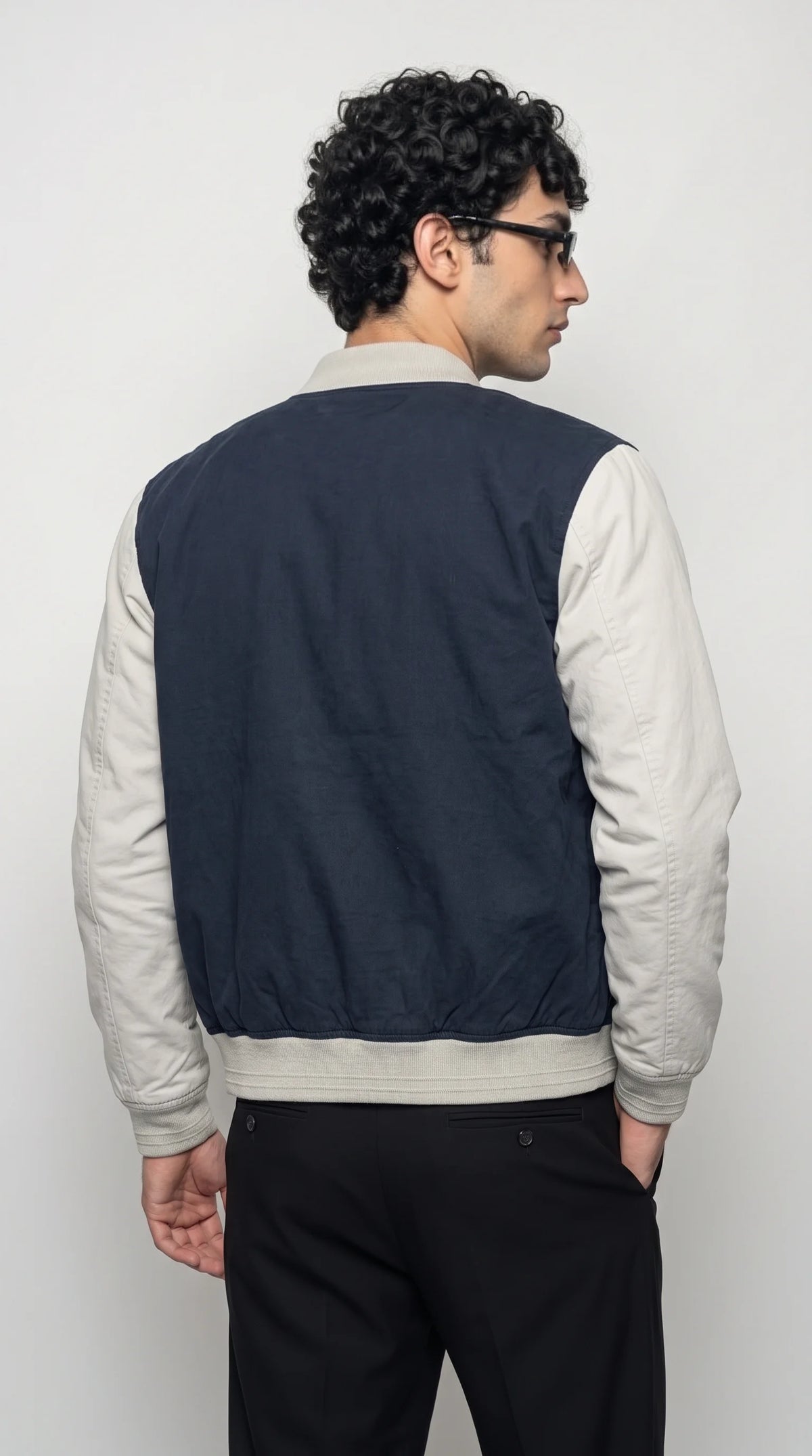 Dark navy-blue cotton bomber with light-grey sleeves, two side welt pockets, a full front zip and a relaxed waist-length silhouette, offering a practical layering piece for casual menswear, everyday errands and understated urban outfits.