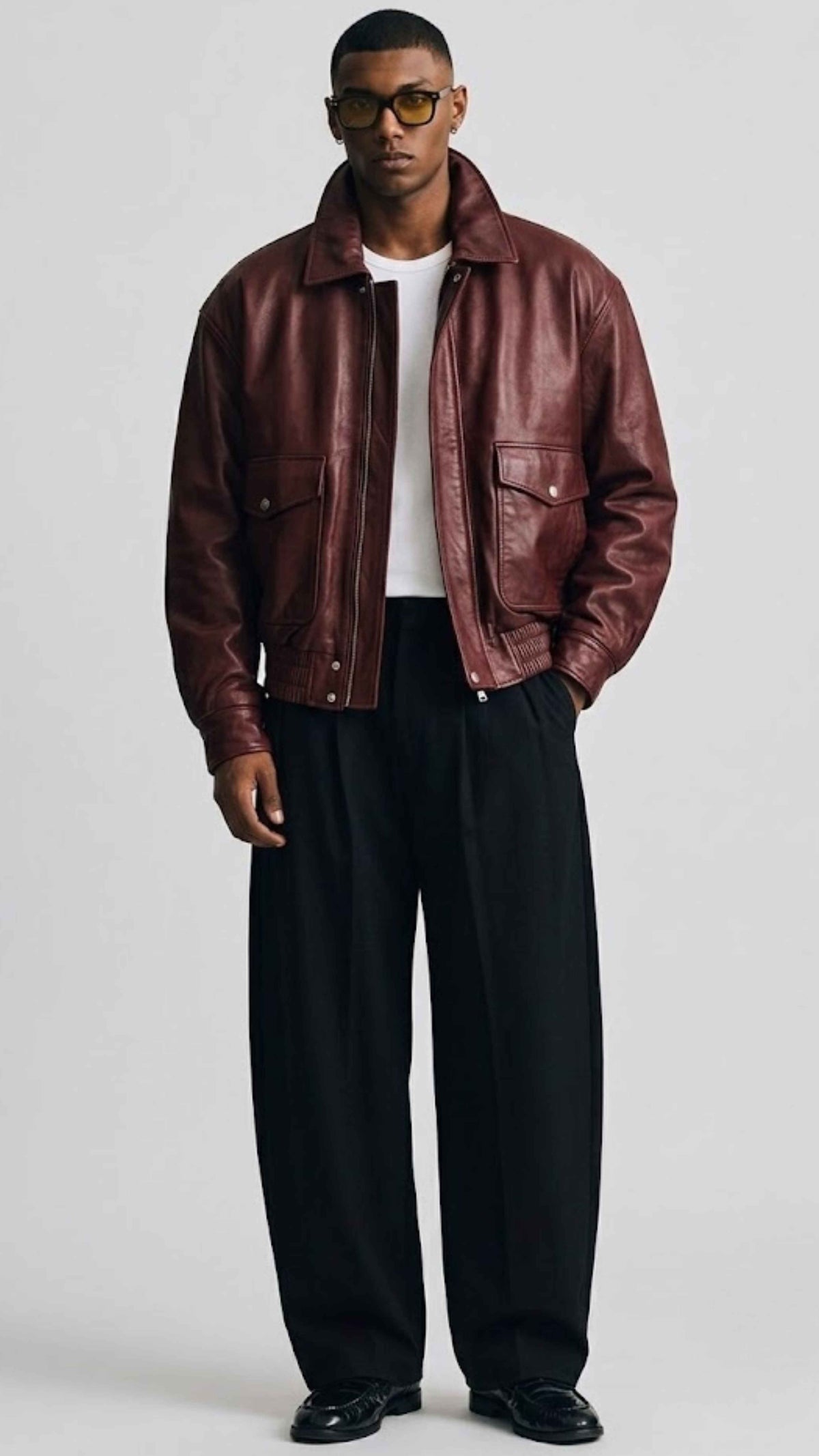 Front view of men wearing dark red oversized leather bomber jacket with full zip closure and ribbed collar.