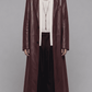 Full-length front view of model wearing an elegant dark red vine leather trench coat with a waist belt and button closure