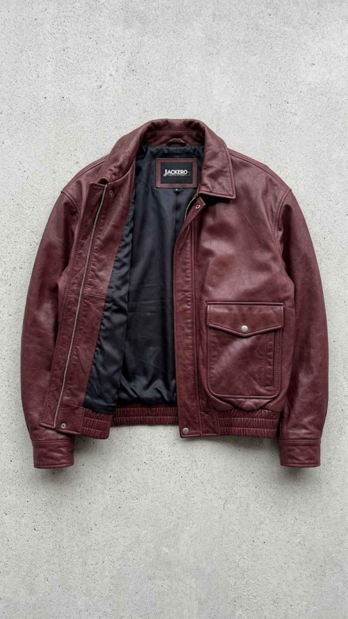 Interior view displaying smooth viscose lining and deep inside storage pocket of dark red bomber jacket.