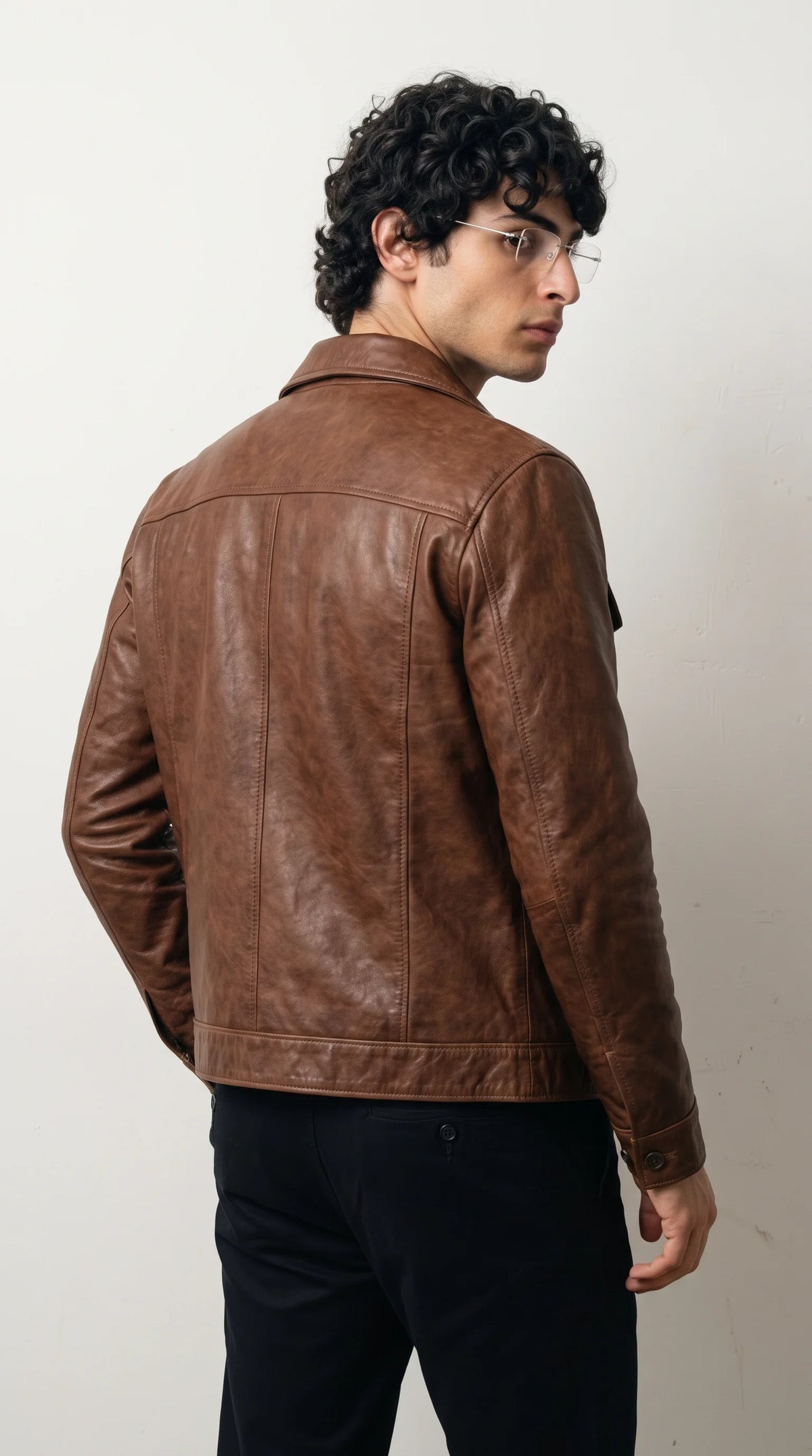 Dark tan brown genuine leather jacket showcasing a broad shoulder yoke, vertical stitched back panels, a clean straight hem and long leather sleeves, combining durable-looking construction with a streamlined heritage menswear silhouette.