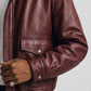 Close-up shot of rib-knit collar and heavy-duty front zipper on deep burgundy leather bomber jacket.