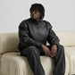 Detailed shot of high-neck wrap closure and custom metal snap button hardware on black textured leather jacket.