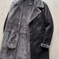 Detailed view of buttons and shearling trim on a high-quality men's dark grey leather coat.