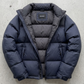 Detailed look at the protective high collar and cuffs of a navy blue quilted puffer jacket.