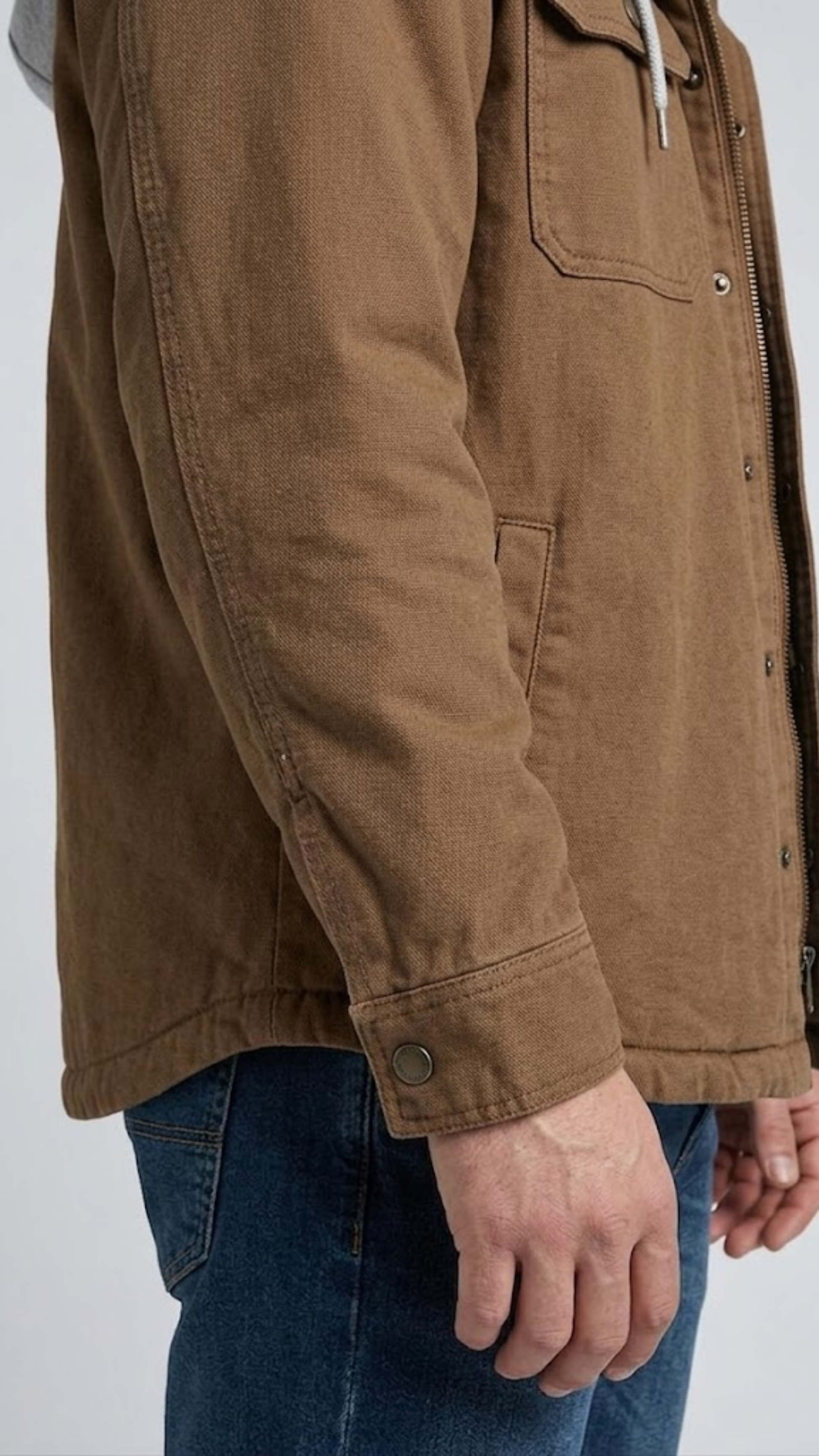 Close-up shot highlighting the thick, rugged canvas fabric texture and reinforced stitching of a dark tan work jacket.