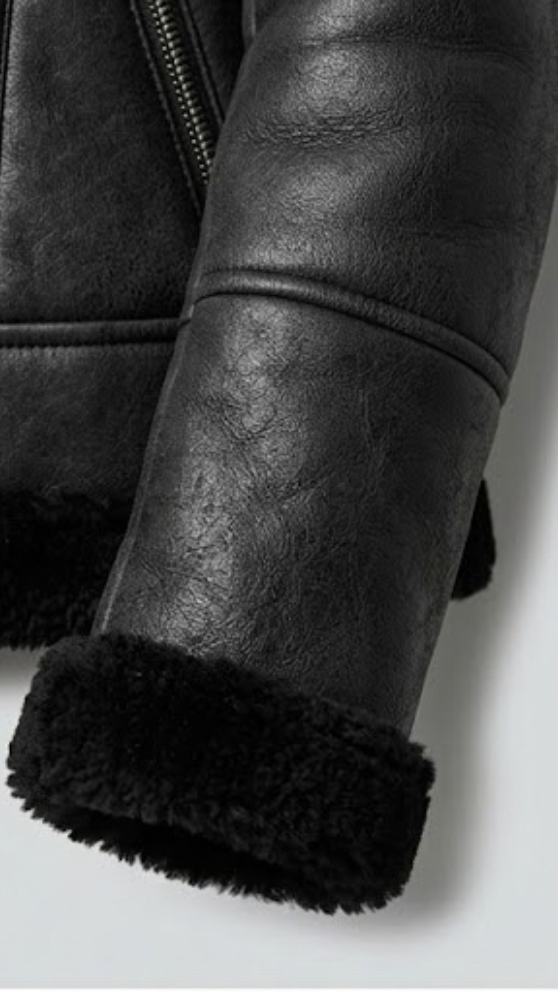 Close-up detail of the plush, soft faux shearling lining and collar on a heavy-duty black leather winter jacket.
