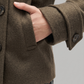 Close-up of a person wearing a brown wool pea coat on a plain background