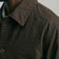 Close-up of a person wearing a brown canvas jacket with a neutral background