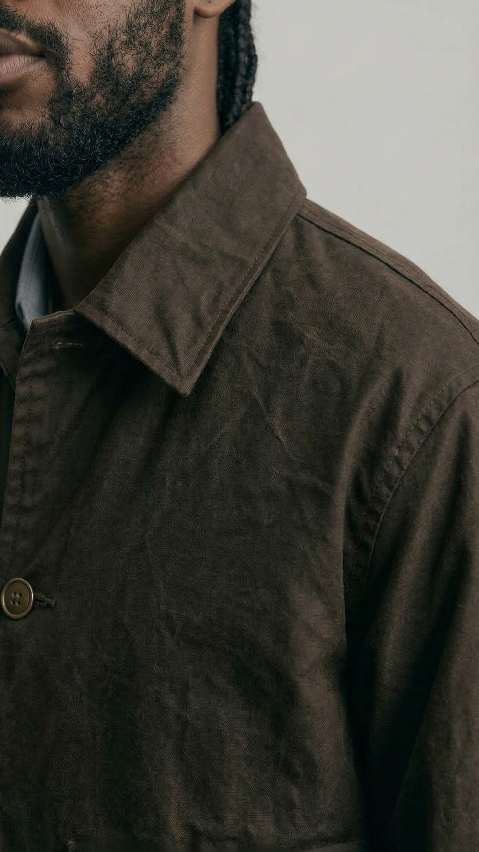 Close-up of a person wearing a brown canvas jacket with a neutral background
