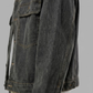 A close-up of a washed dark charcoal denim jacket along the side, shown against a solid gray background.