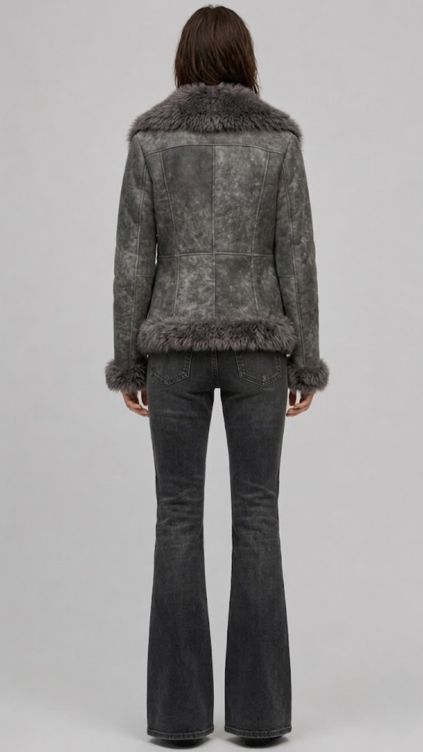 Model wearing a JACKERO fitted grey fur-trimmed shearling coat paired with a white crop top and high-waisted black flare jeans.