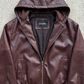 Detailed hardware close-up of a premium maroon hooded leather bomber showing high-grade brass metallic zippers and soft interior lining.