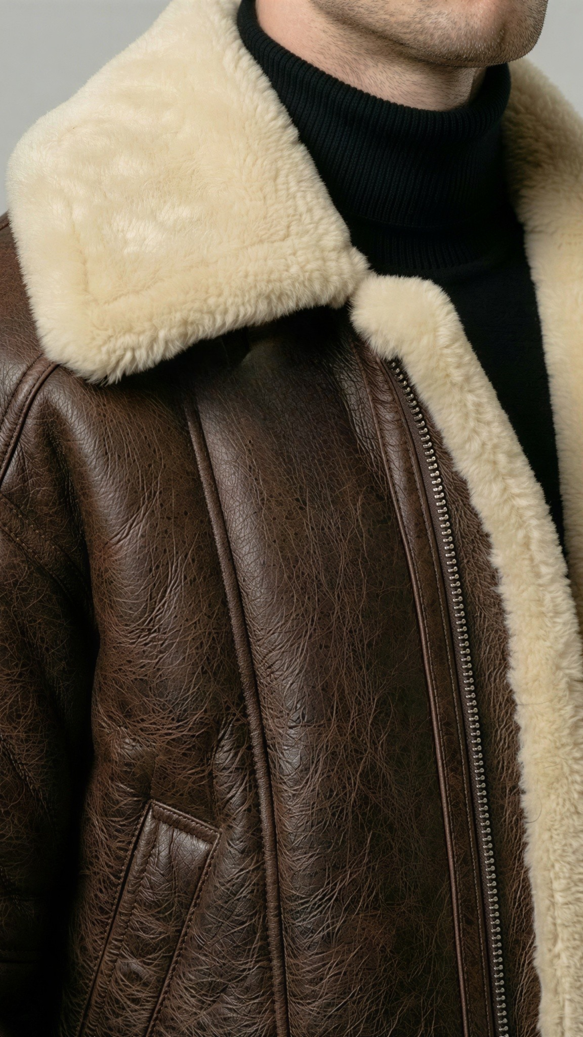 cozy dark brown leather bomber jacket featuring an insulated cream shearling high-collar for wind protection.
