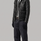 Man wearing a black leather jacket and dark jeans on a gray background
