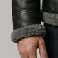 Close-up of a black leather jacket with gray fur lining on a plain background