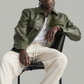 Model wearing a custom-fit sustainable forest green leather jacket standing against a solid grey studio background.