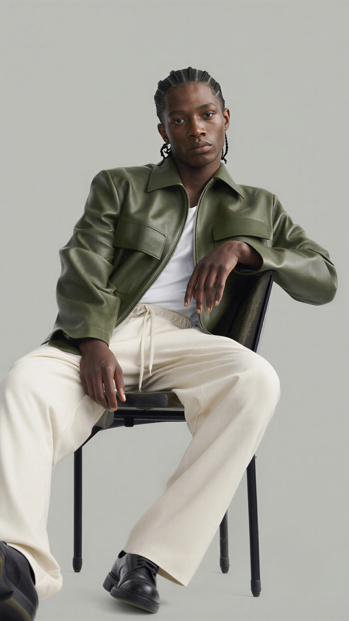 Model wearing a custom-fit sustainable forest green leather jacket standing against a solid grey studio background.